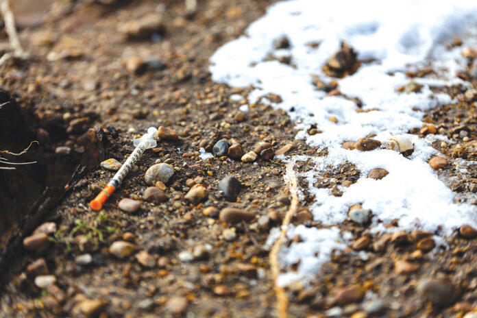 A used syringe that has been discarded on the floor at a popular